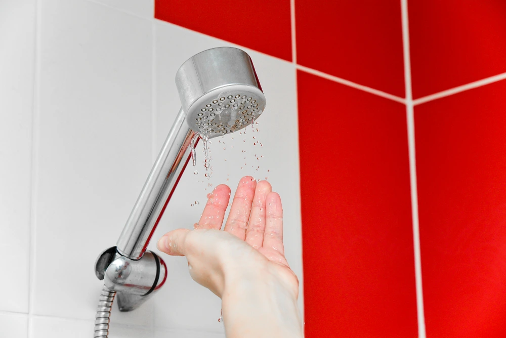 hand under showerhead checking low water pressure